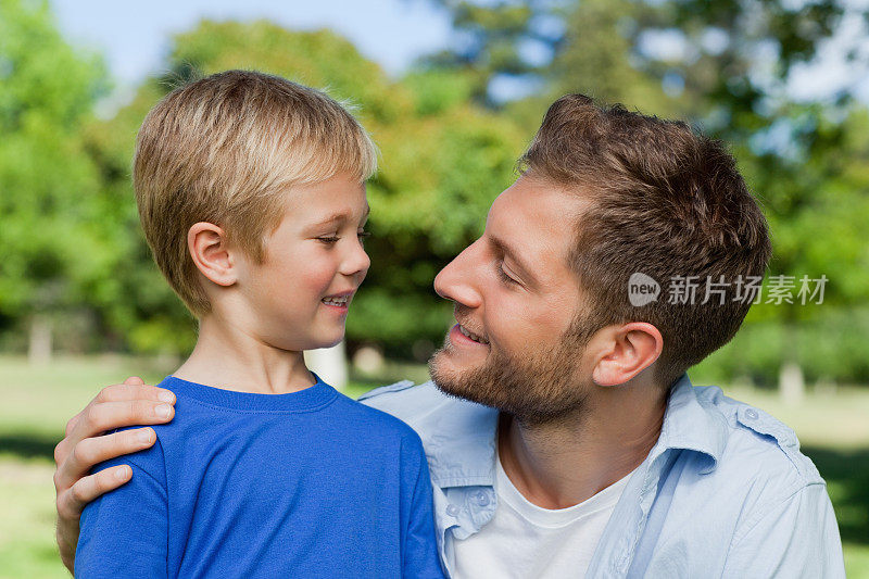 在公园里微笑的父亲看着他的儿子