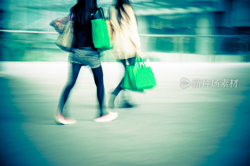 两个女人提着购物袋走着