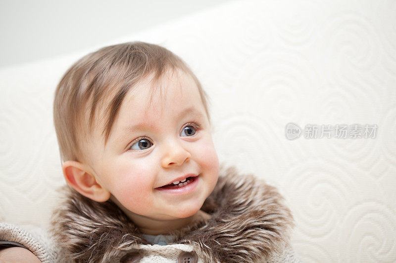 小女孩10个月大，带着毛皮领外套微笑