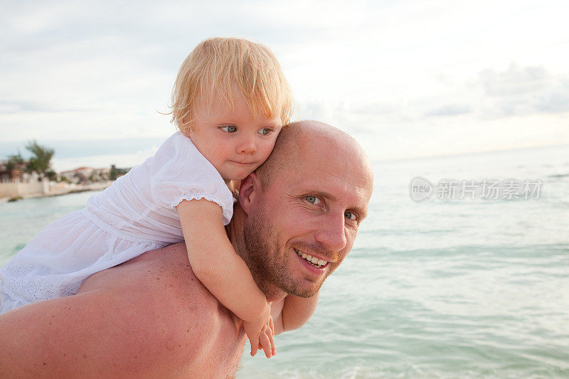 日出时，父亲抱着女儿在海边