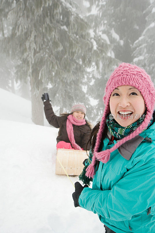 母亲和女儿带着雪橇