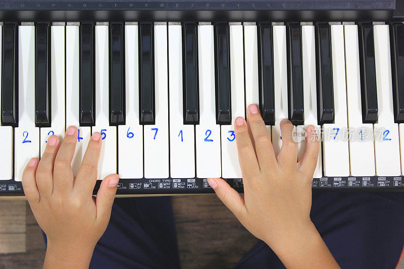 小男孩用手在电子钢琴或键盘上弹奏音乐