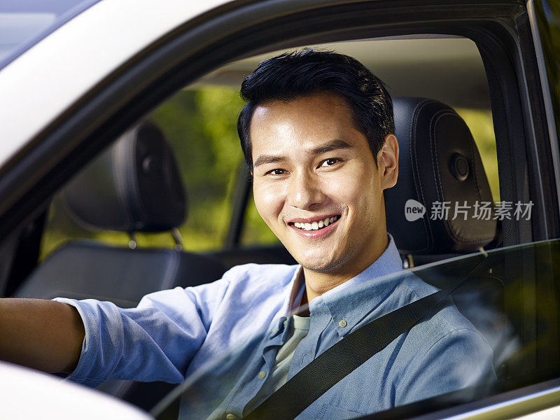 年轻的亚洲成年人系着安全带开车