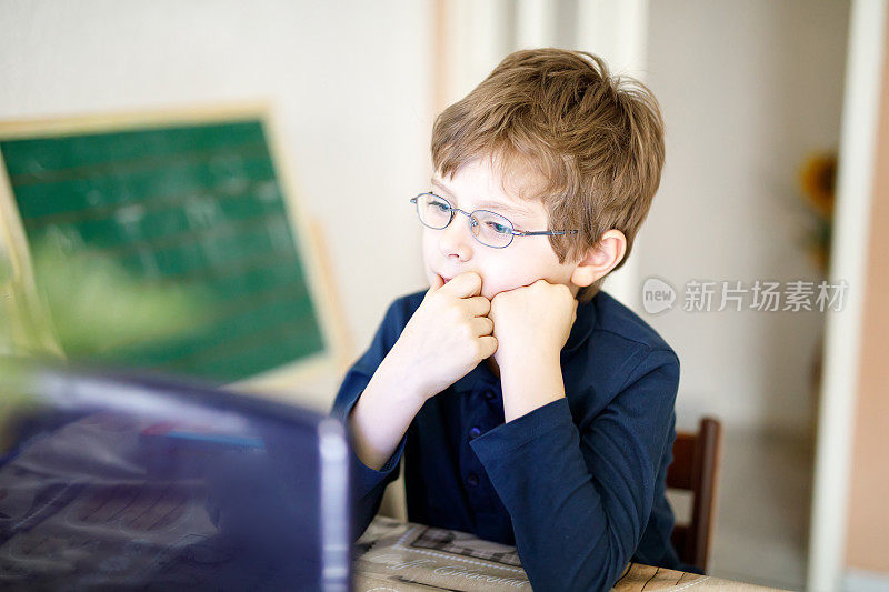 戴着眼镜的小男孩在电脑上做学前作业