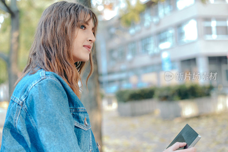 年轻的女学生在城市公园里学习，秋天的时候。