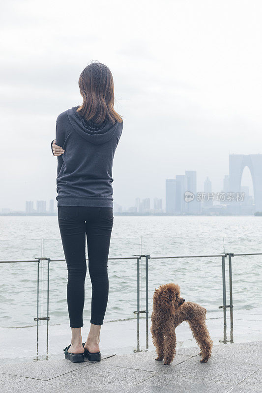 后视图的女人站在码头和她的宠物坐在一边