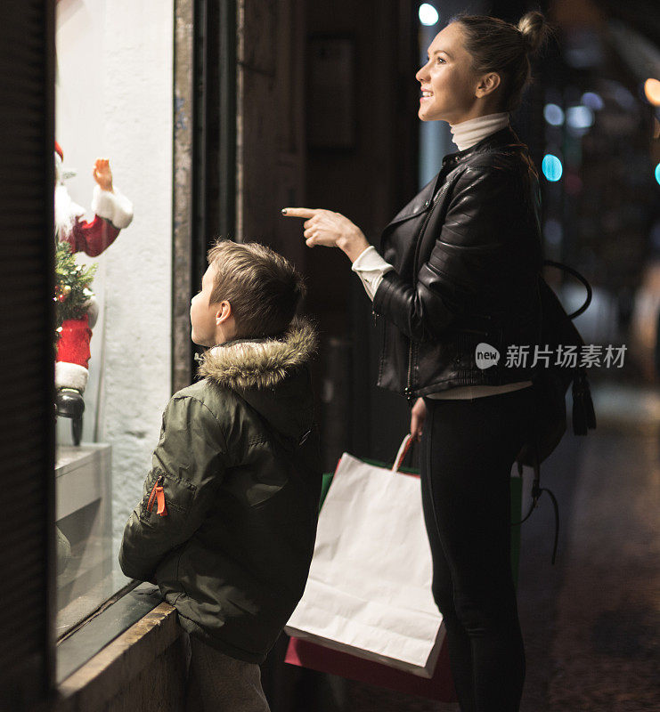 妈妈和她的儿子看着圣诞节商店的橱窗