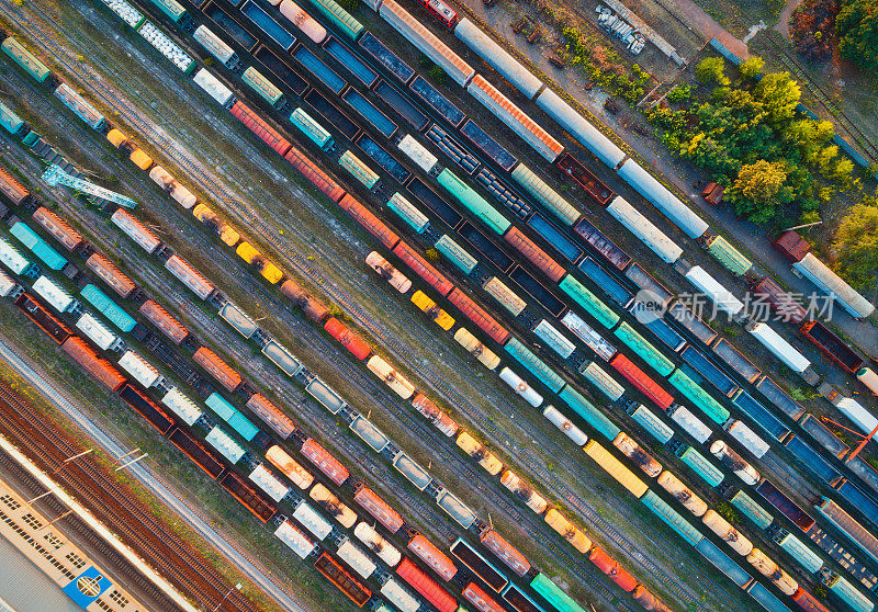 俯视图的彩色货运列车。从飞行的无人机鸟瞰图多彩的货运列车在火车站。铁路上装载货物的货车。重工业。工业概念场景