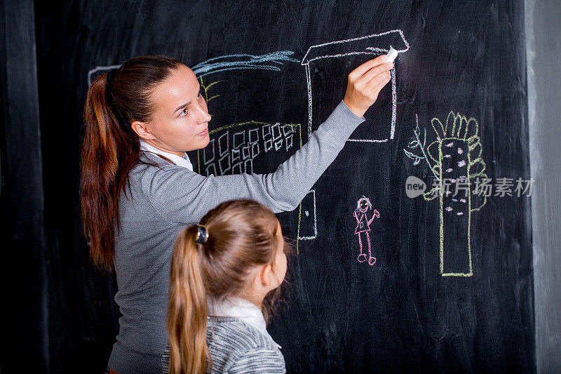 老师和女学生用粉笔在黑板上写字