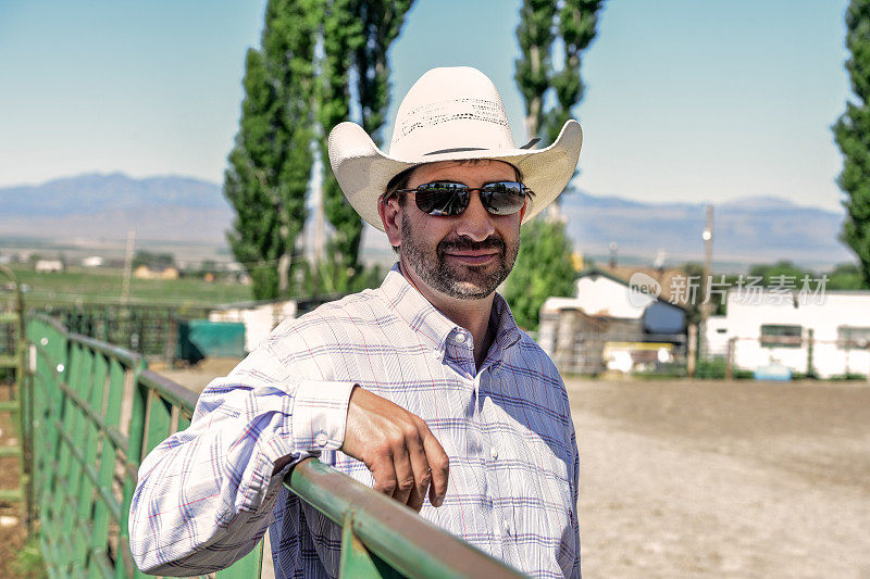 美国犹他州西语叉的牛仔帽牧场主倚靠在篱笆上