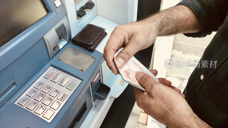 土耳其男子向自动取款机递钱