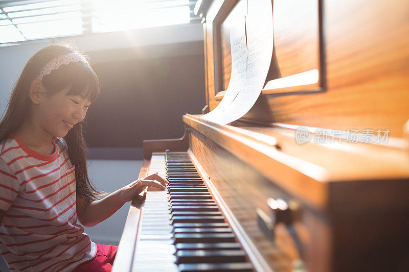 微笑的女孩在课堂上练习钢琴