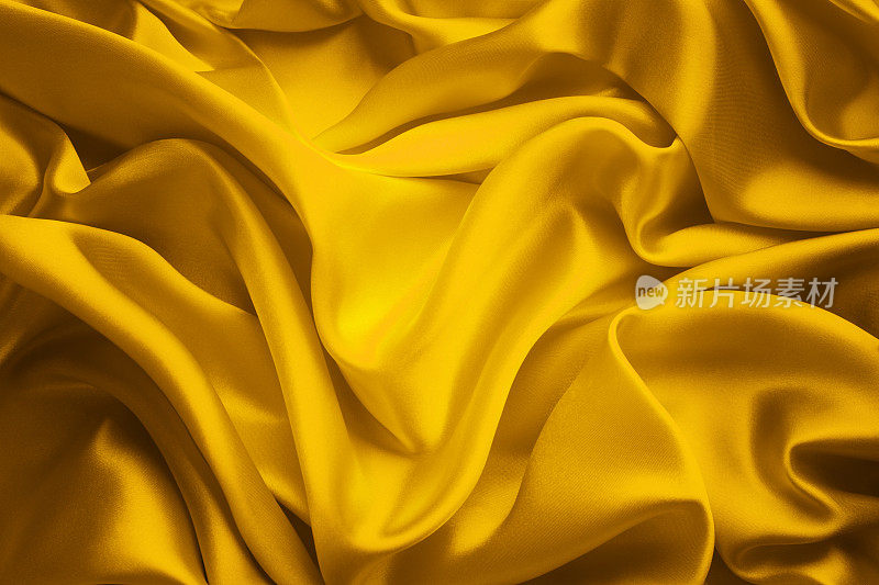 丝绸面料背景，黄缎布波浪，抽象的流动波浪纺织品