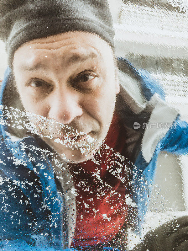 冬天的场景，成熟的男人在清理车上的积雪。用手机拍的照片。