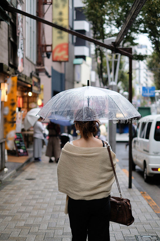 在一个雨天里，一名妇女走在东京神乐坂传统老城的街道上