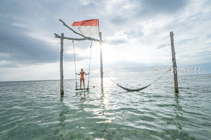 年轻女子荡过大海，美丽的田园诗般的风景。人们旅游度假的概念。