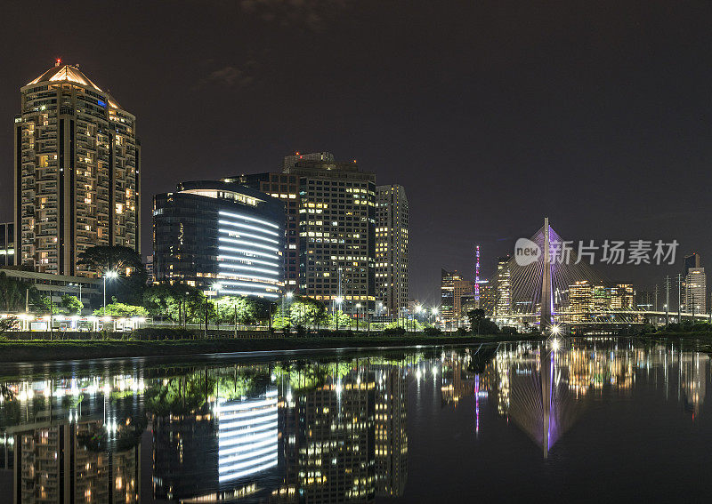 夜晚的天际线与建筑反映在河和斜拉桥的背景，圣保罗，巴西