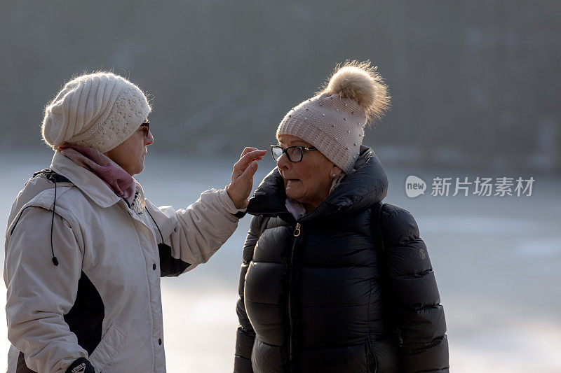 年长的女士们站在结冰的湖边