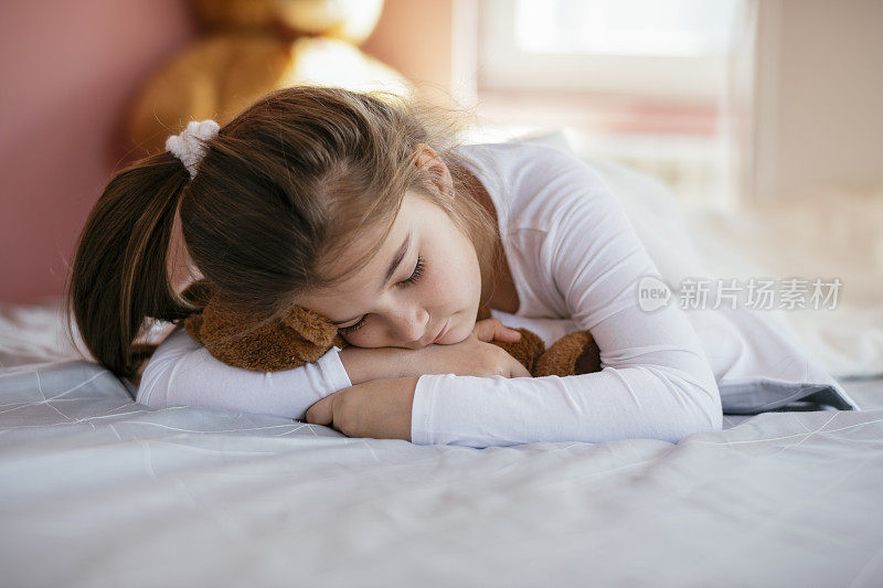 漂亮女孩和她的泰迪熊在床上