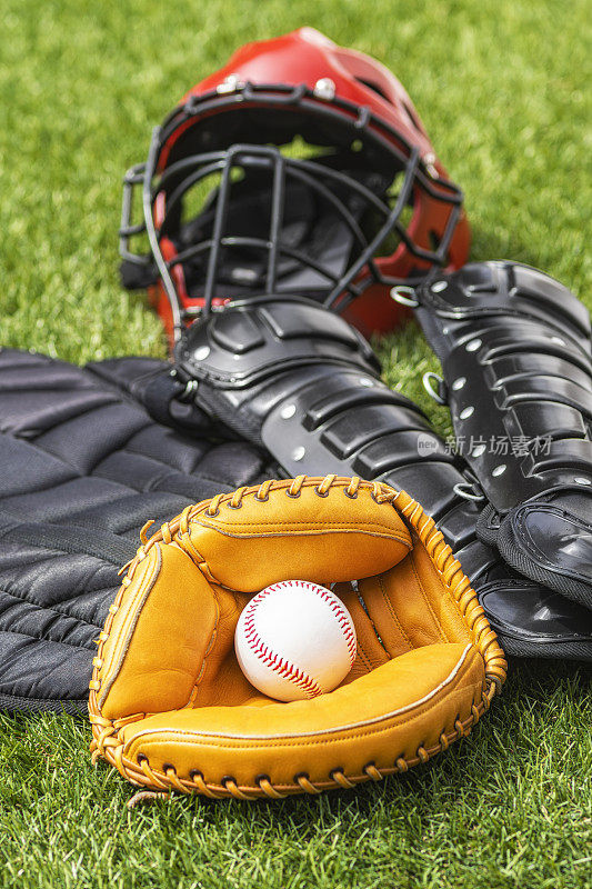 特写的棒球在捕手手套和一套棒球捕手的装备的背景