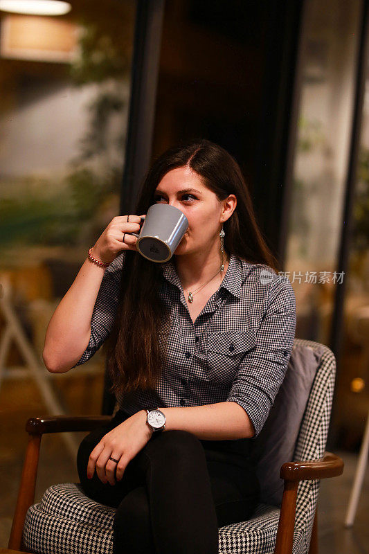 年轻快乐的女人喝着咖啡，在咖啡馆里放松。
