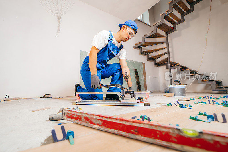 修理工的手在地板上的瓷砖切割机上切割瓷砖。近距离