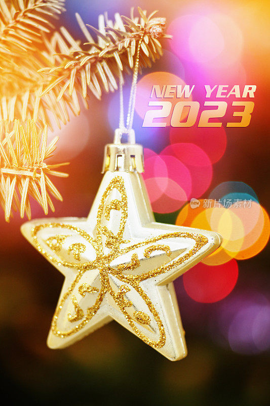 2023年装饰拜年。悬挂在树枝上的装饰明星和圣诞树在模糊的彩色背景下的装饰品