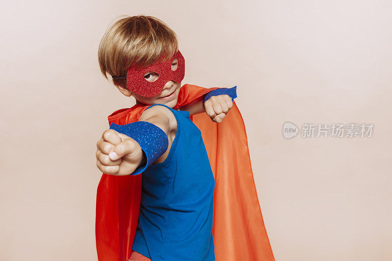 可爱的小超级英雄男孩在红色斗篷和面具