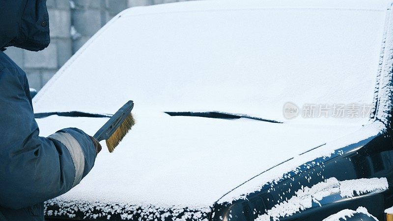 降雪后，一名妇女正在清洗家用汽车