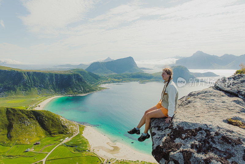 侧视图的女旅行者正在考虑从上面的风景优美的海滩和罗弗敦群岛的山脉