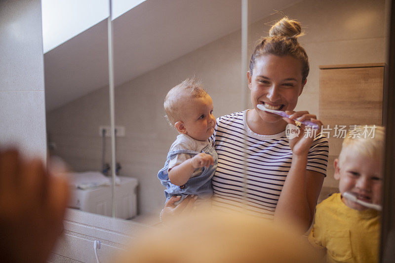 一位母亲和她的儿子在早上刷牙的时候看着镜子里的对方