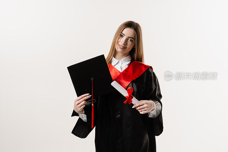 身着黑色毕业服，头戴黑色毕业帽的快乐学生在白色背景下微笑。毕业女孩高中毕业，庆祝学业成就。硕士学位证书在手。
