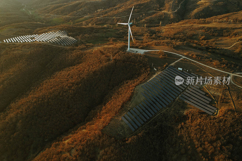 日落时的太阳能电池板和风力涡轮机。可再生能源