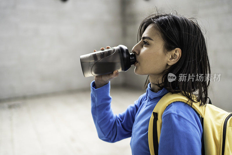 年轻女子在户外运动后喝水