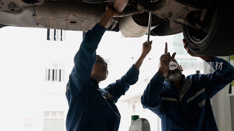 女修理工在资深修理工的指导下进行车辆维修