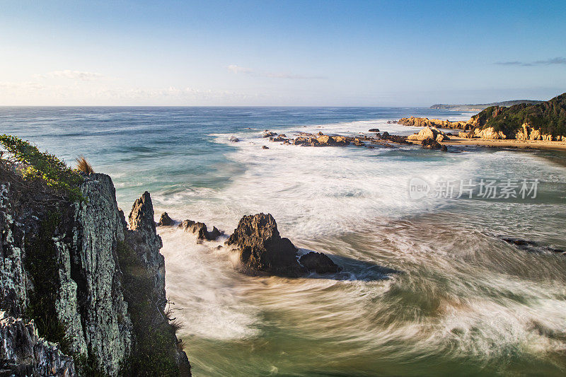 长时间曝光平滑的海浪翻滚到岩石海滩