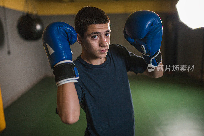自信的男运动员戴着拳击手套在健身房训练