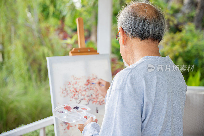 老年老人在画布上用毛笔和水彩画图画艺术品