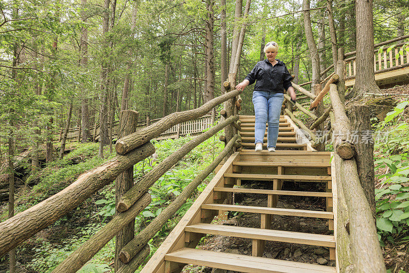 在宾夕法尼亚州的布什基尔瀑布徒步旅行路线上导航:一名女游客在宾夕法尼亚州的波科诺山脉的自然地标上导航