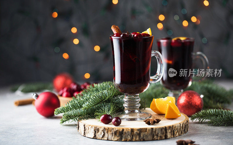 一杯热葡萄酒配上蔓越莓和肉桂棒，圣诞背景带散景。