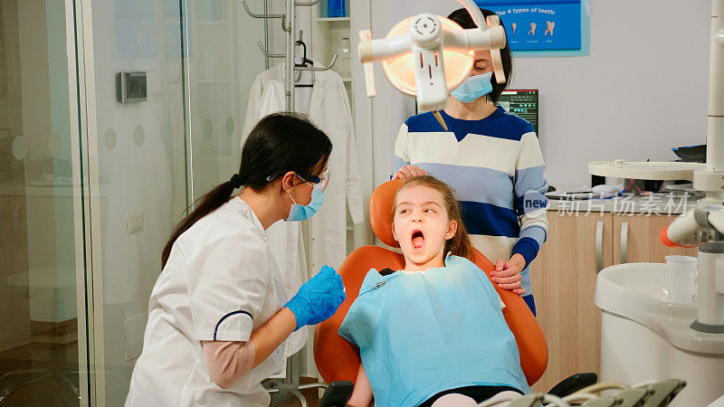 儿科牙医兼助理在口腔诊所治疗女童病人
