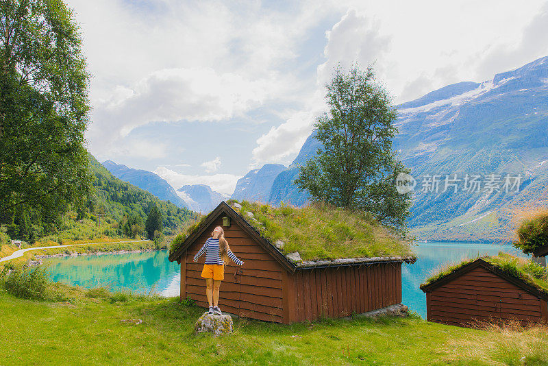 快乐的女游客在挪威的山村漫步，欣赏美丽的湖景