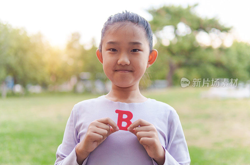 小女孩拿着字母“B”