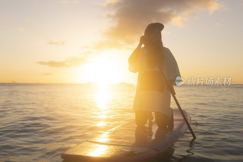 在一个美丽的日落，一个女人在开阔的海面上划船