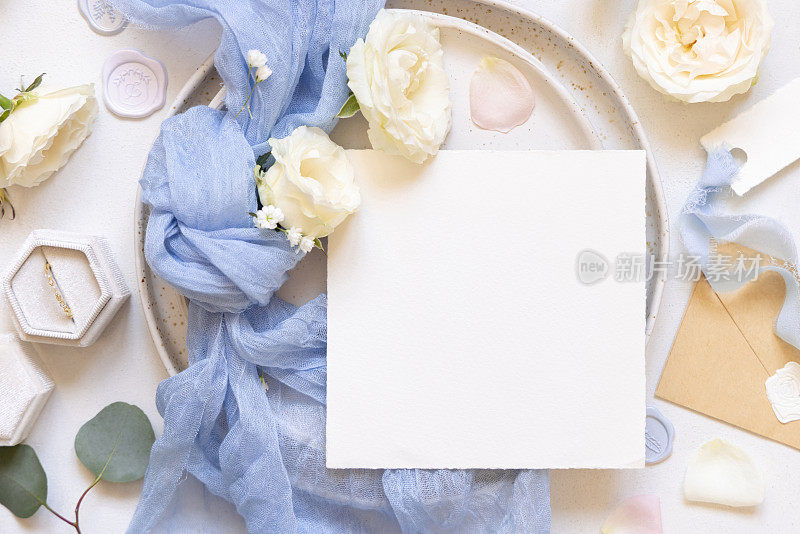 卡片附近的蓝色薄纱织物结和奶油玫瑰在盘子顶部查看复制空间，婚礼模型