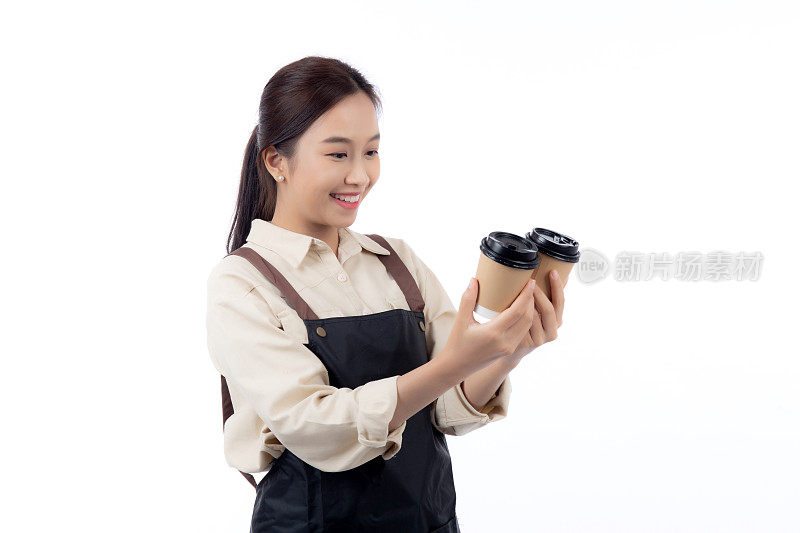 快乐的年轻亚洲女咖啡师穿着休闲的工作服，开心地拿着外卖咖啡杯，孤立的白色背景，快乐的咖啡师展示外卖咖啡，小企业或创业。