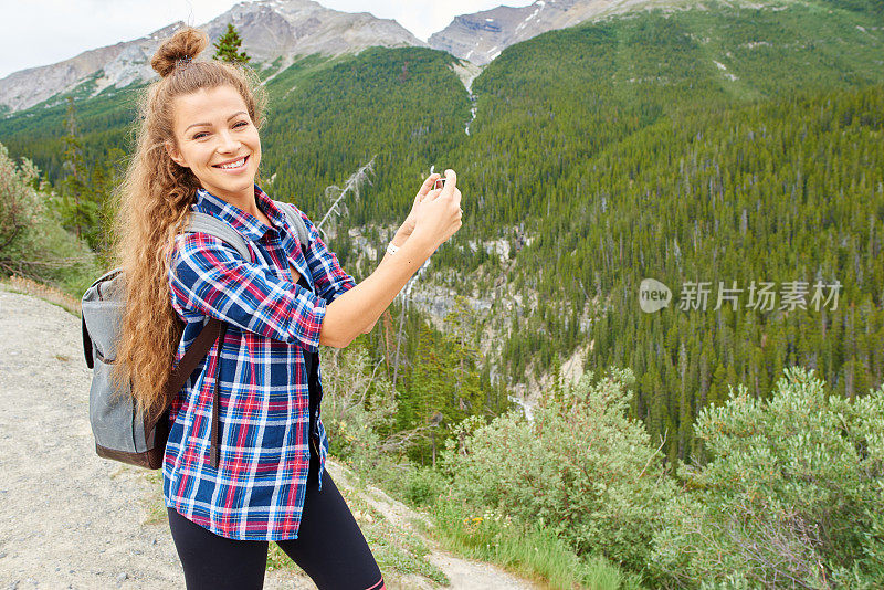 年轻漂亮的女背包客用手机拍照