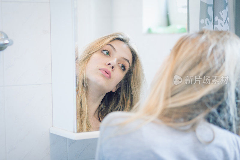 美丽的金发女孩，早晨的头发和嘴唇在浴室的镜子前固定