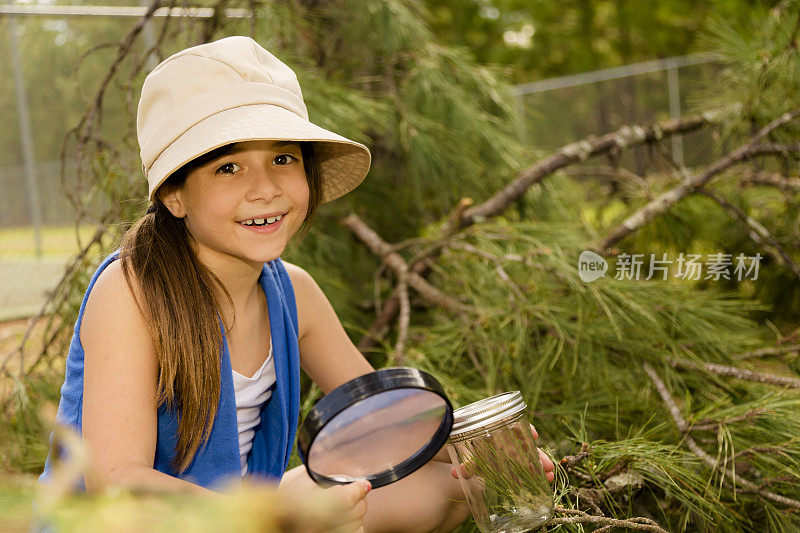 教育:可爱的小女孩在公园里拿着放大镜。科学。