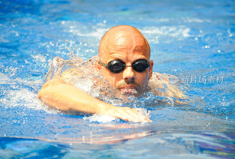 年轻的职业光头游泳运动员在游泳池里自由泳